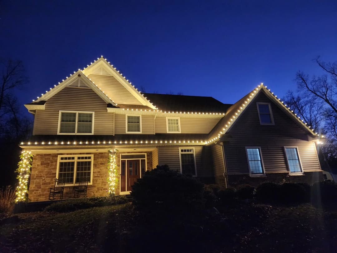 Elegant two-story home illuminated with festive lights against a twilight sky.