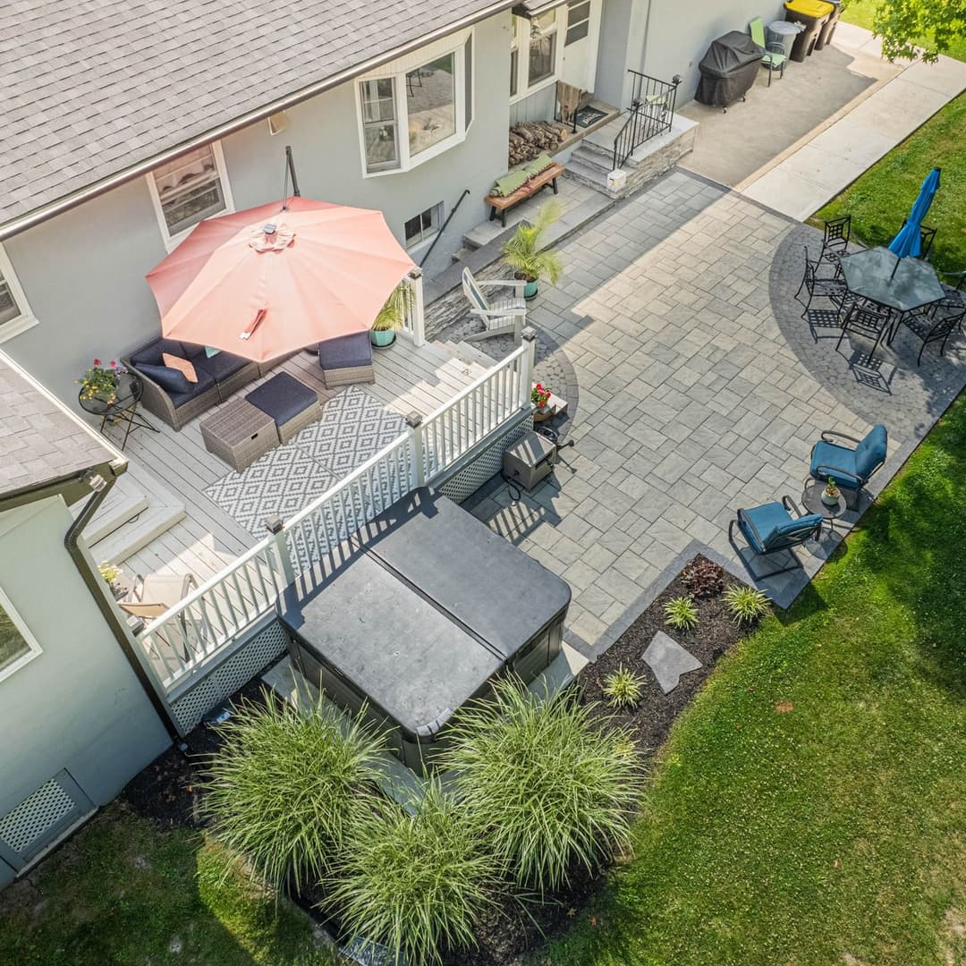 Aerial view of a well-landscaped backyard with a patio, seating area, and outdoor hot tub.