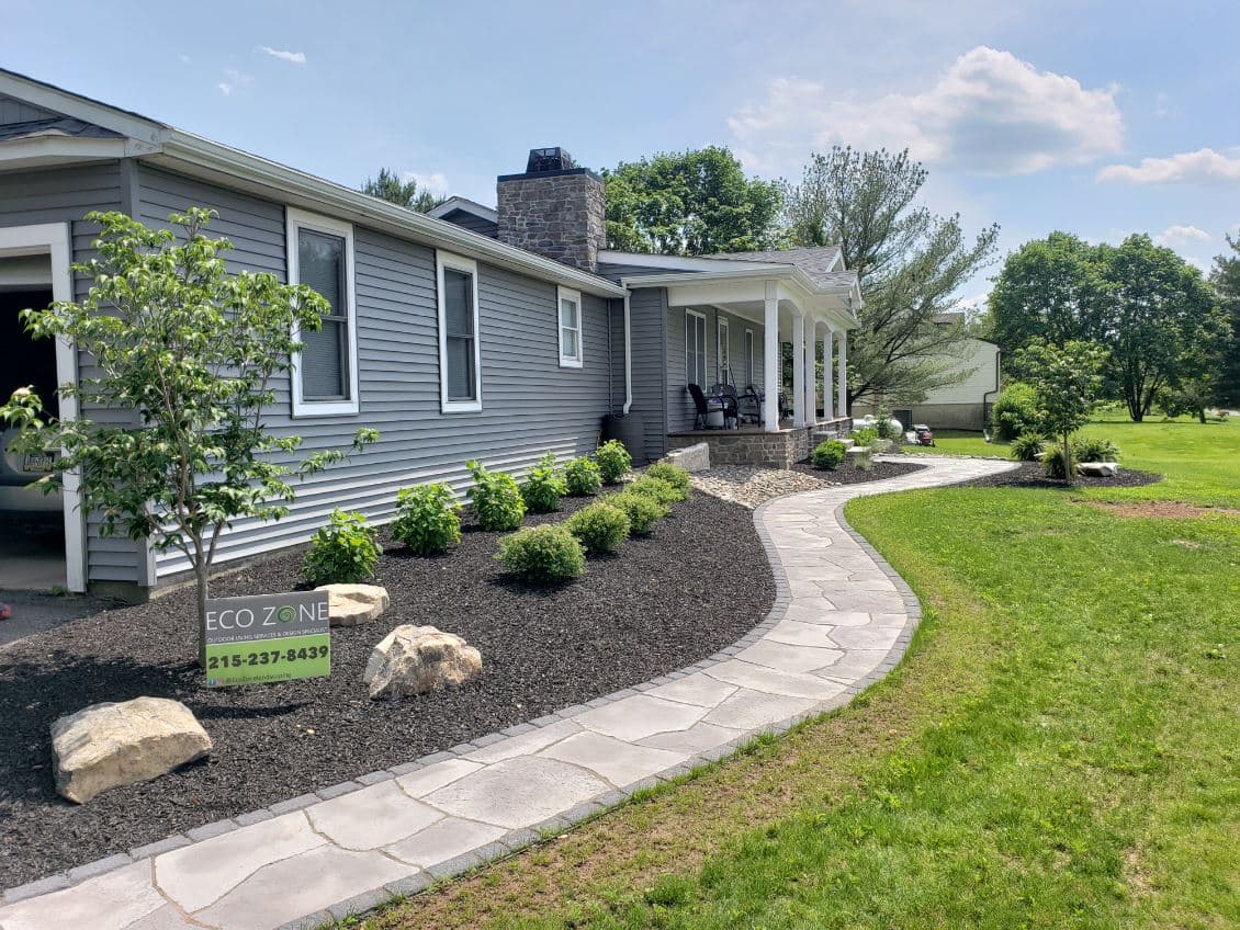 Modern home exterior with landscaped garden, stone pathway, and Eco Zone sign.