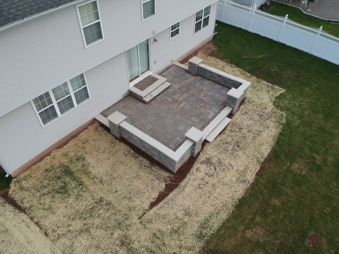 Aerial view of a newly constructed patio with stone seating and freshly landscaped yard.
