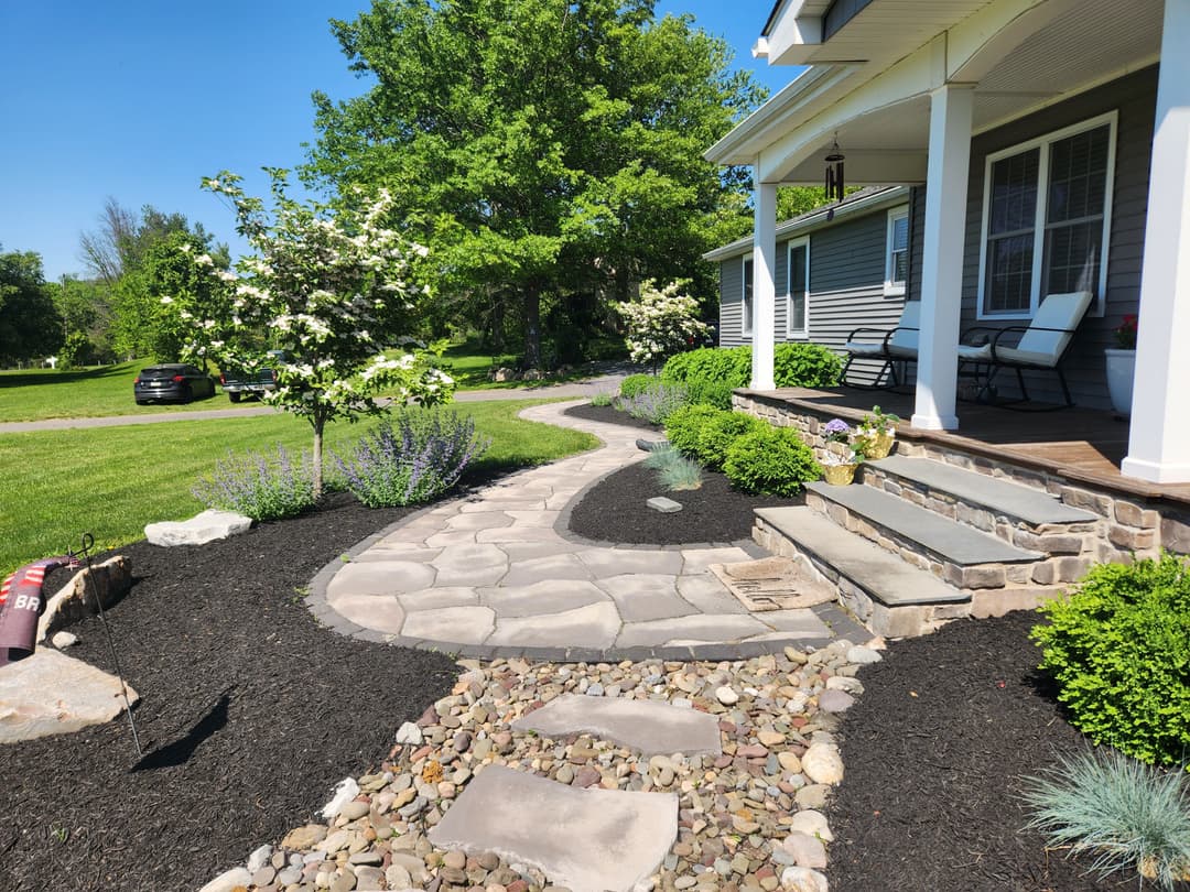 Beautifully landscaped garden featuring a winding stone pathway, flowers, and a charming porch.