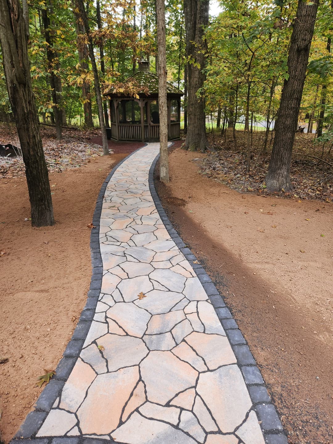 Curved stone pathway leading to a grassy area, featuring decorative lights along the edge.