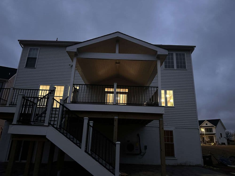 Two-story home at dusk with lit windows and a covered patio.