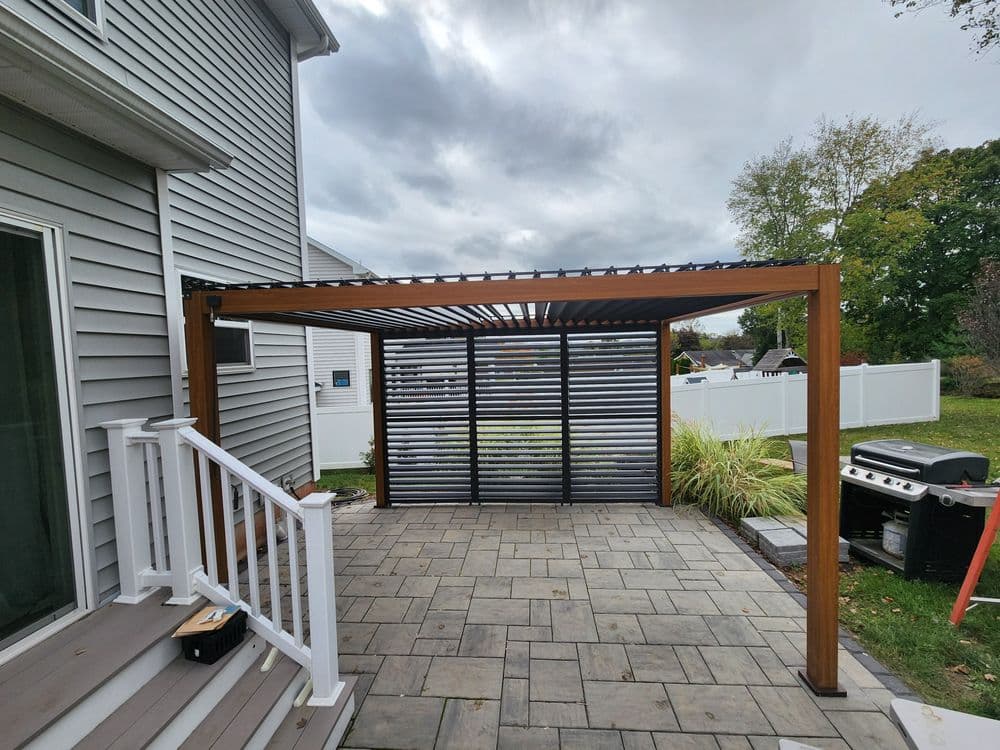 Modern wooden pergola with slatted design on a patio, surrounded by greenery and BBQ grill.