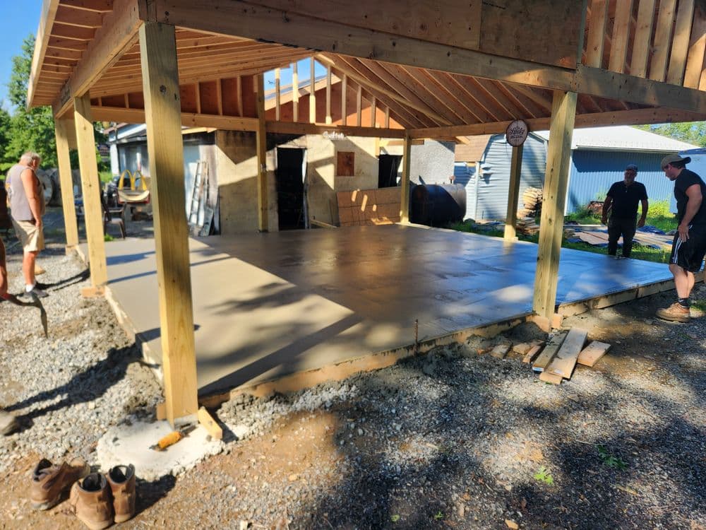 Construction site with workers pouring concrete slab for a structure's foundation.