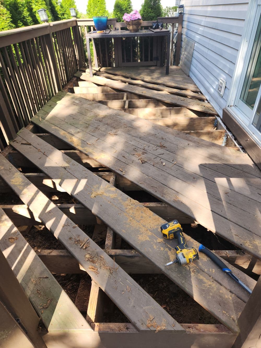 Damaged wooden deck with missing panels and tools scattered on the floor.