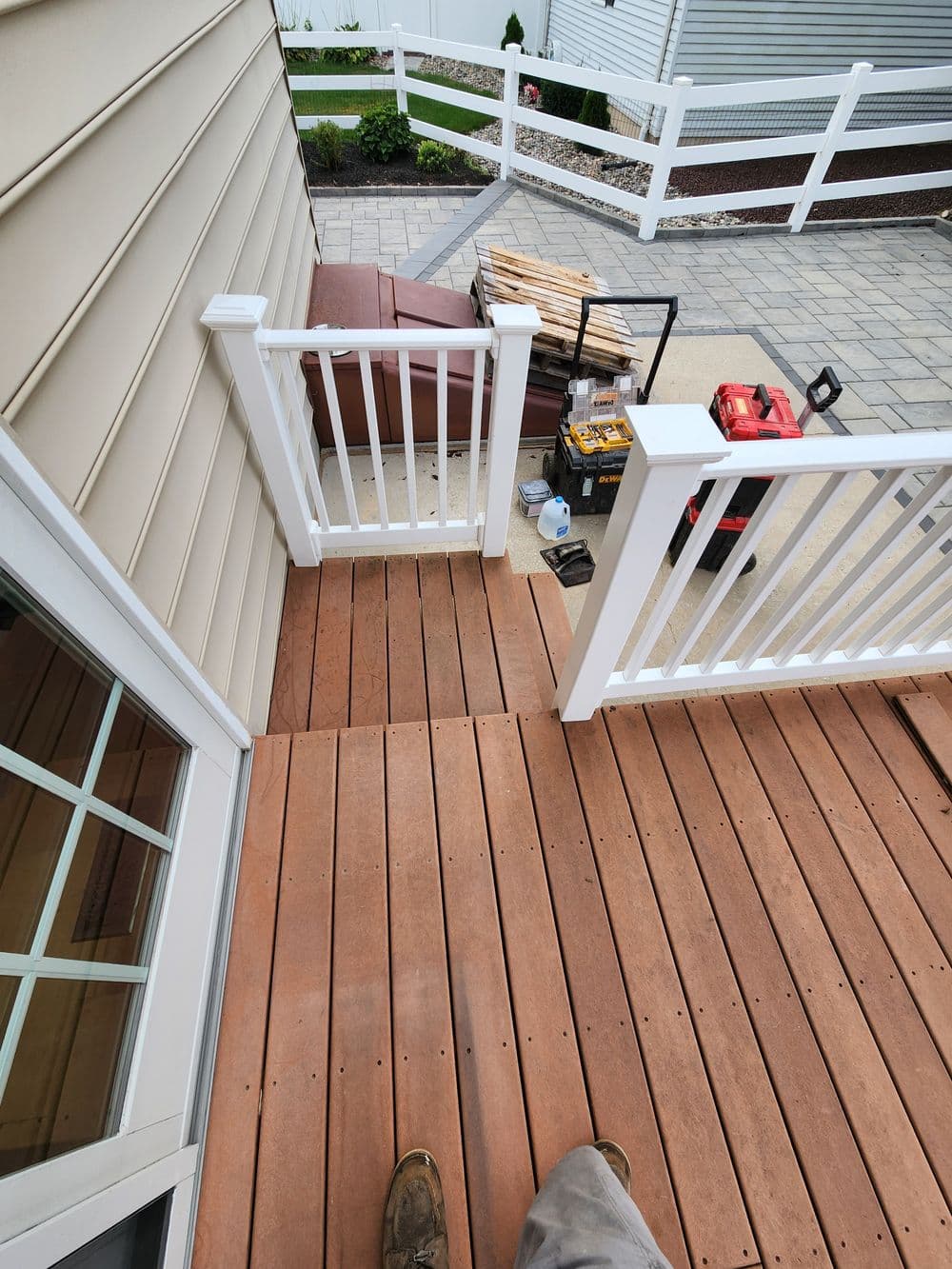 Deck installation with railings, tools, and a seating area in a residential outdoor space.