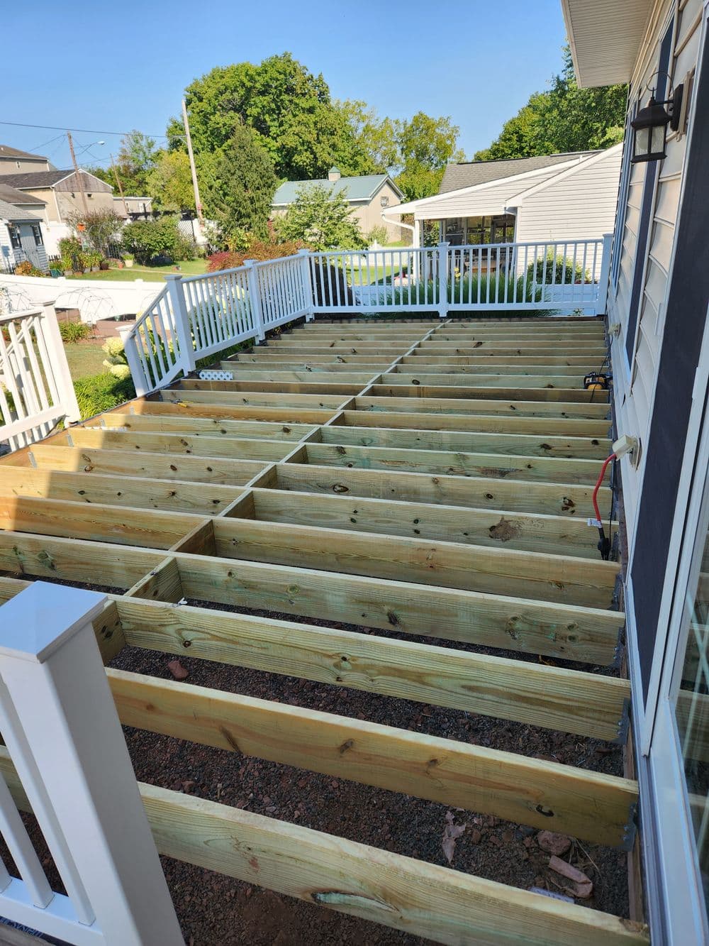 Wooden deck framing under construction, showcasing beams and railings in a residential setting.