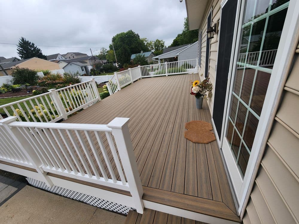 Composite deck with white railings and potted sunflowers, featuring a cloudy sky backdrop.