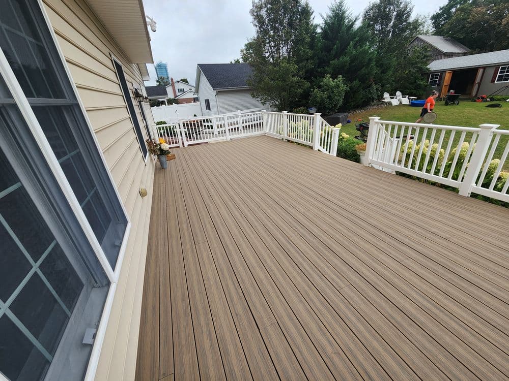 Spacious outdoor deck with wooden flooring and surrounding greenery on a residential home.