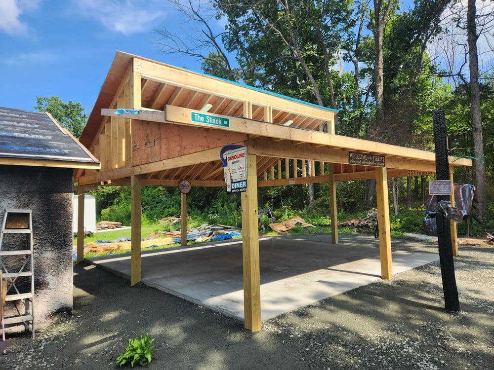 Newly constructed outdoor storage shed with wooden frame in a forested area.