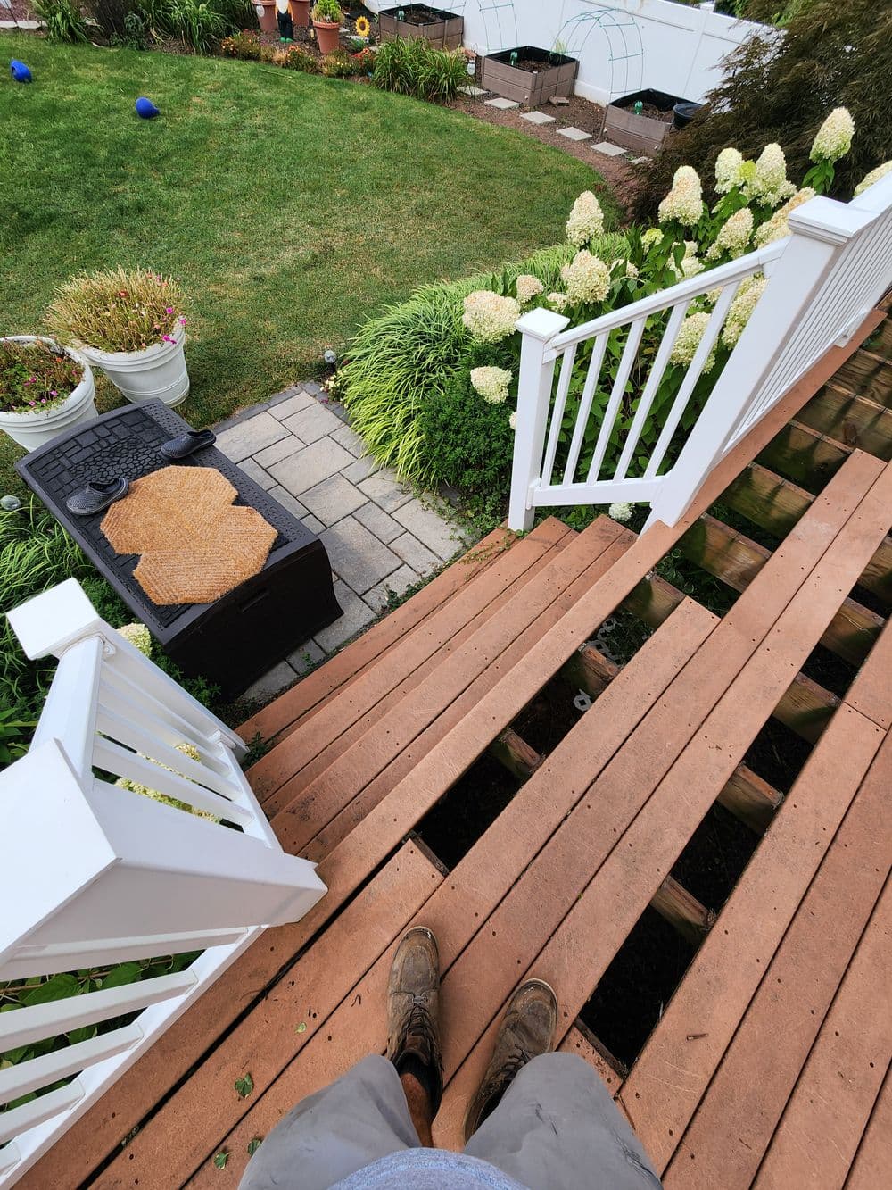 View from above a wooden deck leading to a landscaped garden with hydrangeas and a seating area.