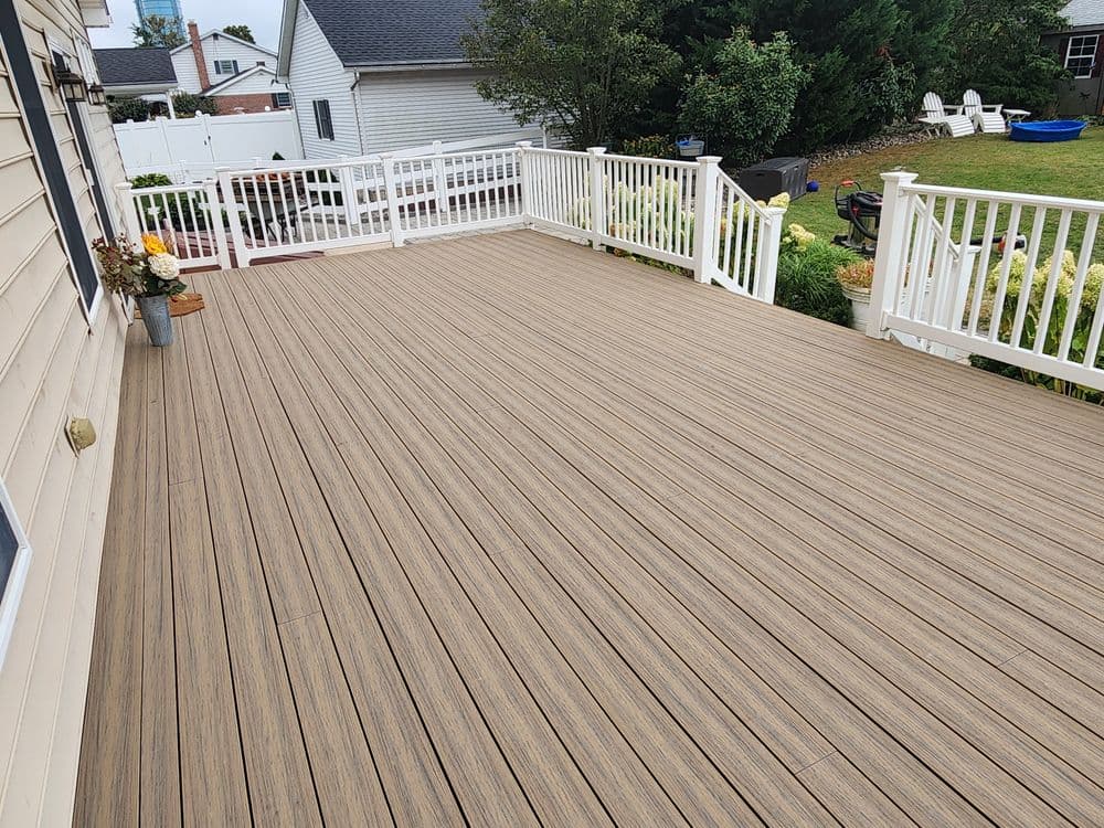 Spacious wooden deck with white railings and green backyard scenery. Perfect for outdoor gatherings.