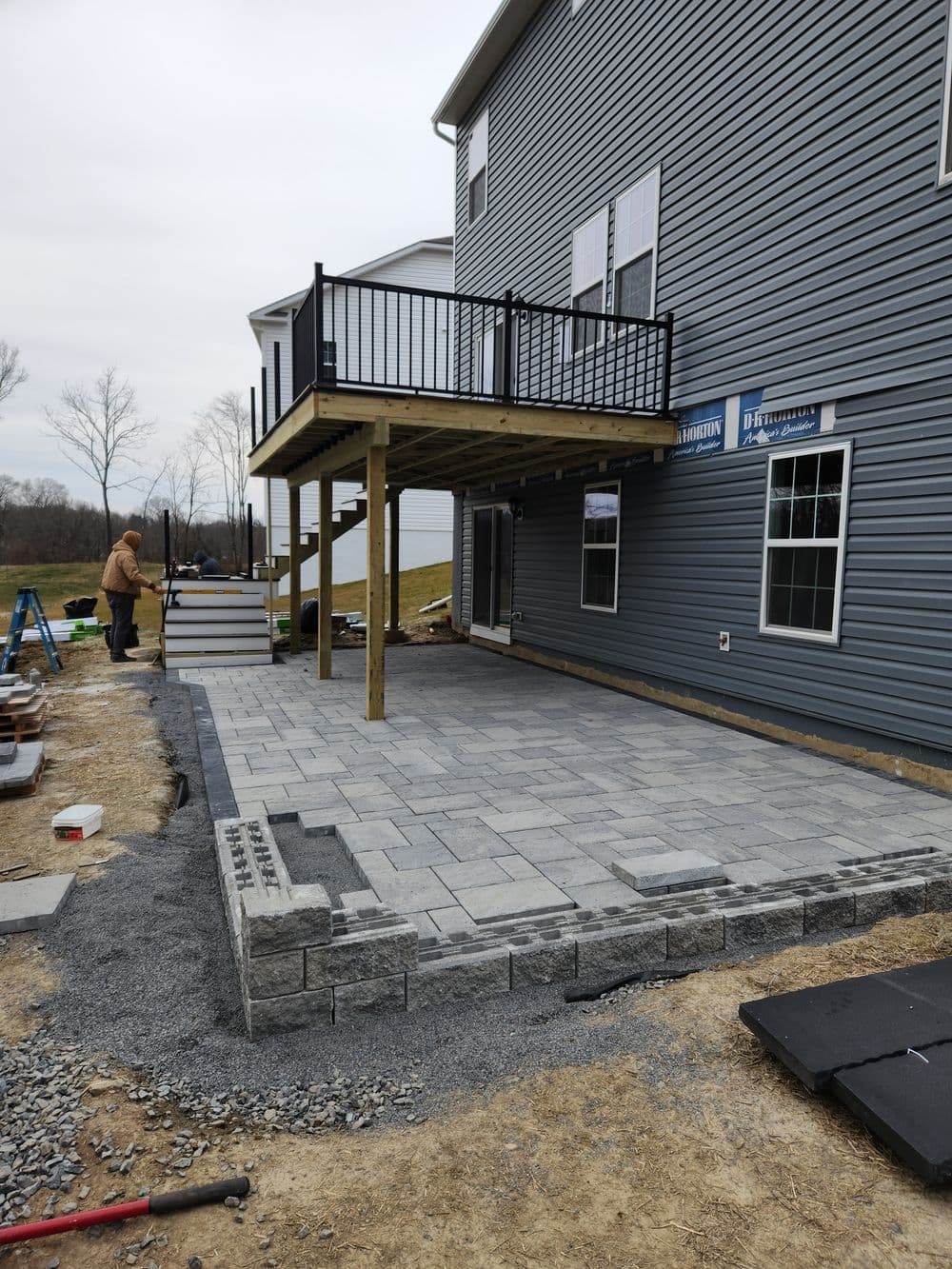 Patio installation with pavers and new deck at a residential home under construction.