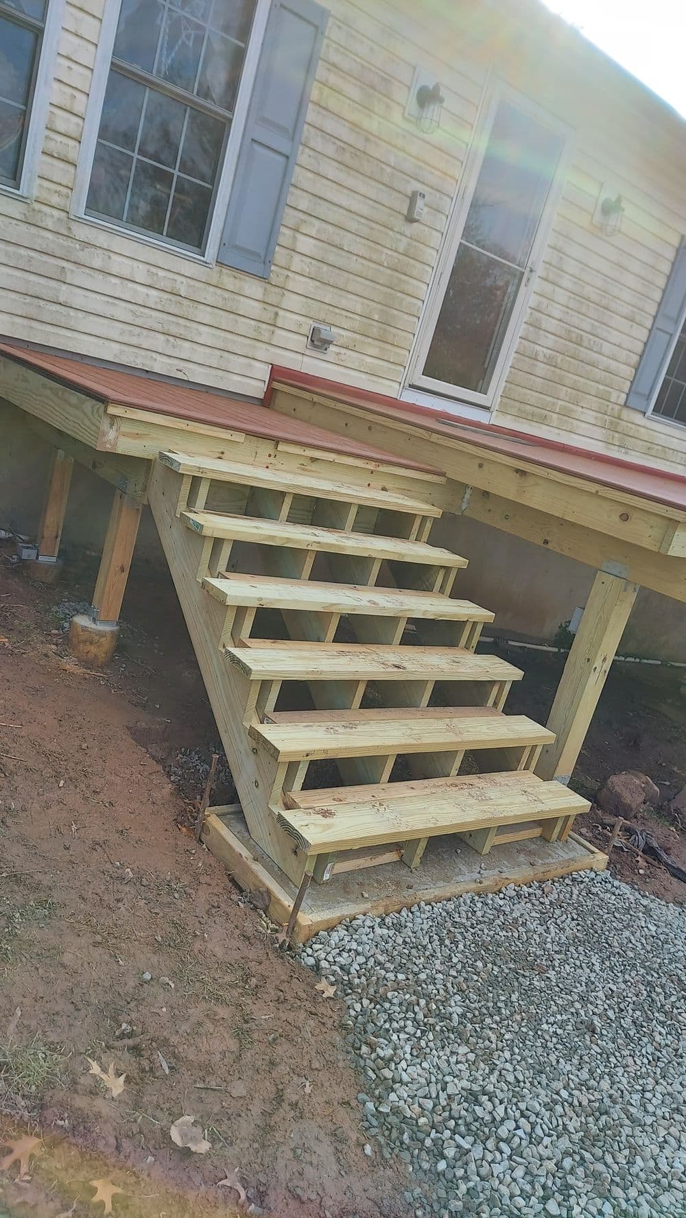 Wooden stairs leading to a house deck, featuring multiple steps and a clear path.