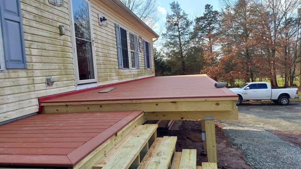 Newly built wooden deck attached to a house with steps, showcasing quality craftsmanship.