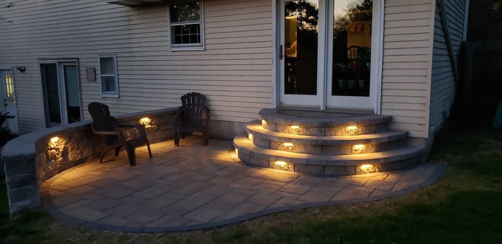 Patio with illuminated steps and seating area, enhancing outdoor ambiance at dusk.