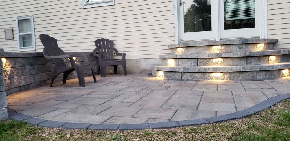 Patio with stone steps and LED lights, featuring two Adirondack chairs.
