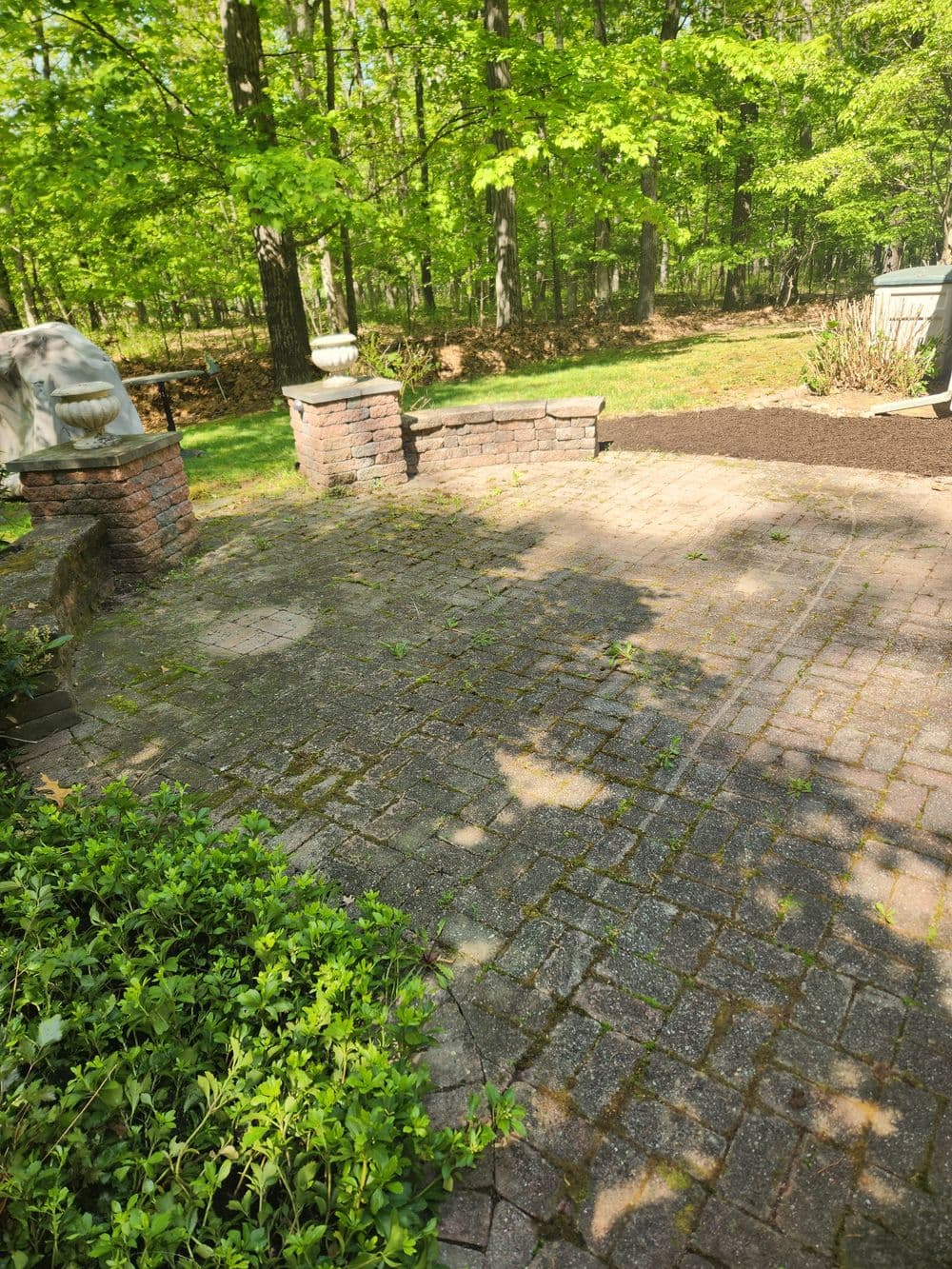 Stone patio surrounded by lush greenery and garden features in a serene outdoor setting.