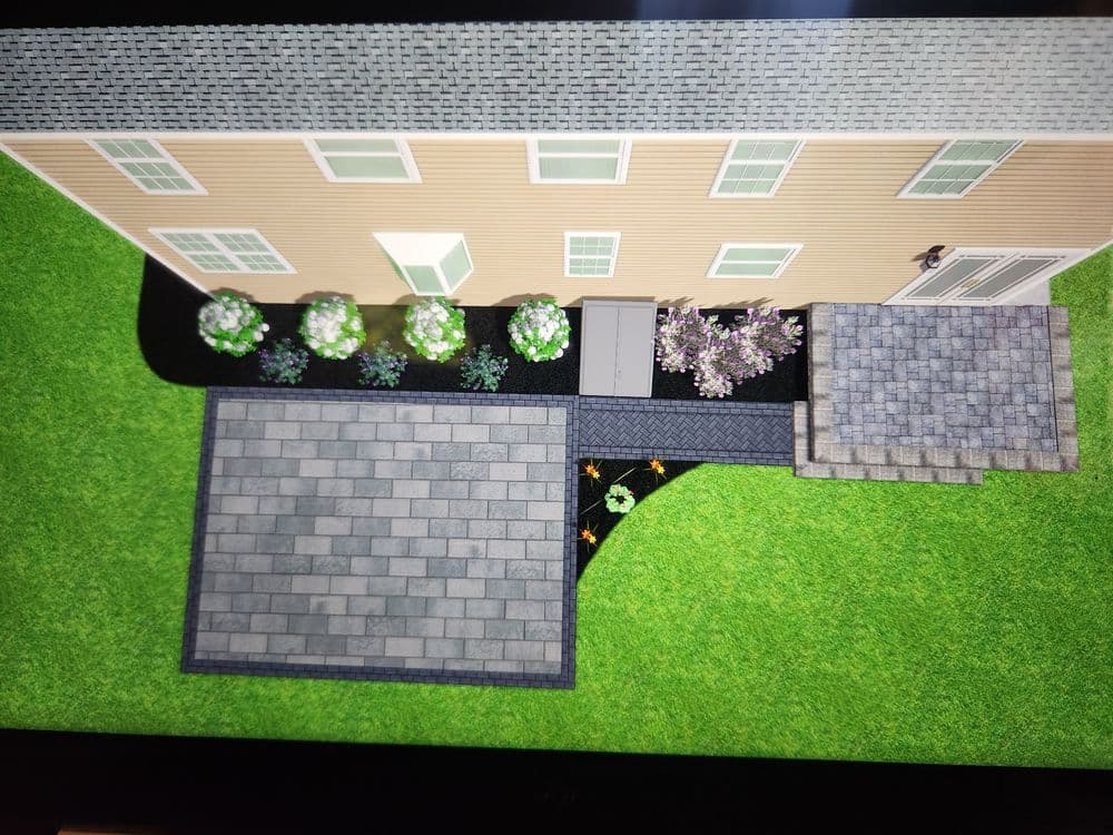 Aerial view of a landscaped backyard featuring flower beds, pavers, and a pathway.
