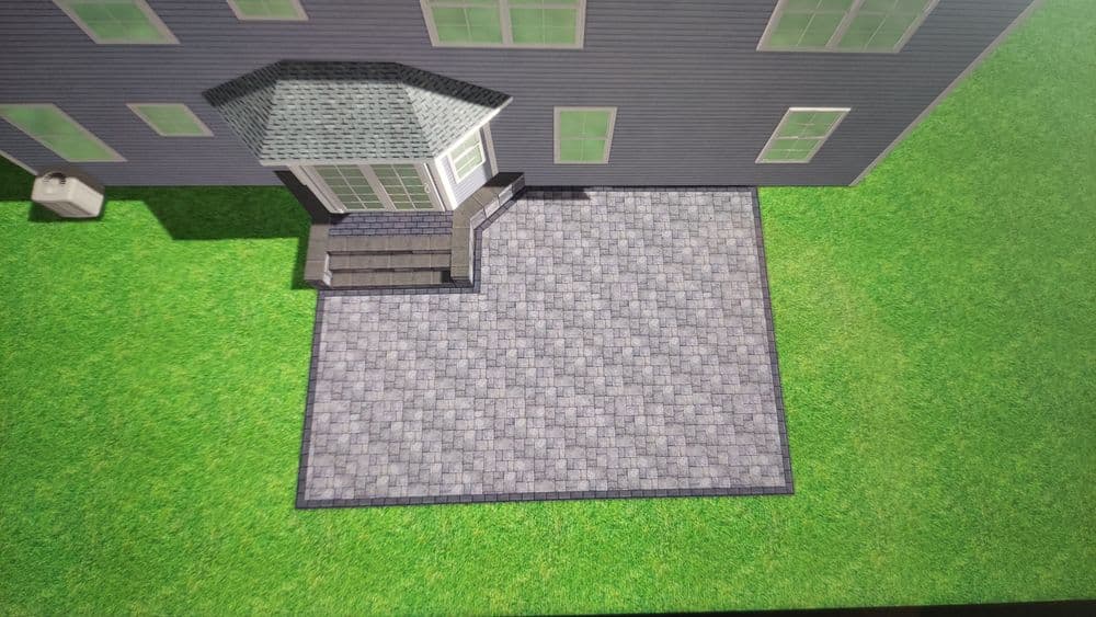 Aerial view of a paved patio area beside a house with green grass surroundings.