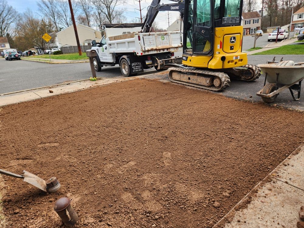 Construction site with a mini-excavator and freshly leveled dirt for landscaping.