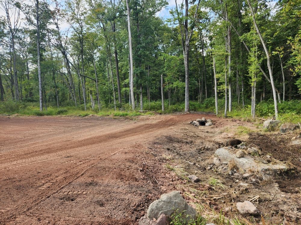 Cleared land with dirt area and tree line, showcasing nature and construction preparations.